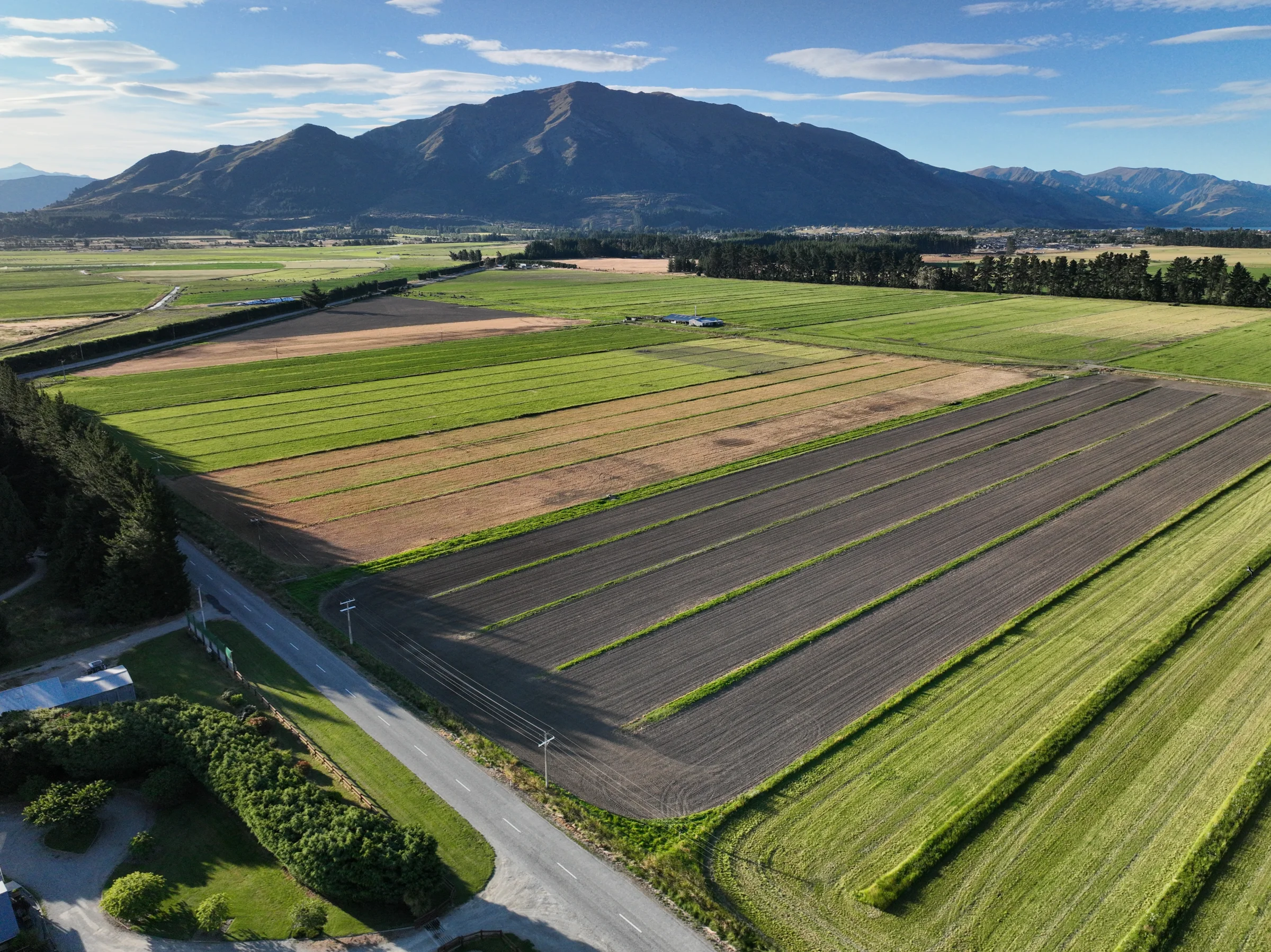 Wide aerial view of valley farmland beneath a mountain range